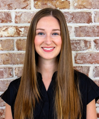 Dr. Kaylie Couch headshot on brick wall